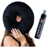 Almohadilla negra para piercing con agujero, sostenida por una persona, junto a spray para piercings