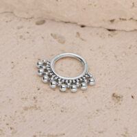 Clicker de septum de titan plateado con bolas Clicker de septum plateado con pequeñas bolas sobre un fondo de piedra texturizada