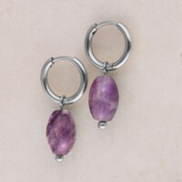 Dos aros de plata con colgante de amatista violeta sobre fondo beige