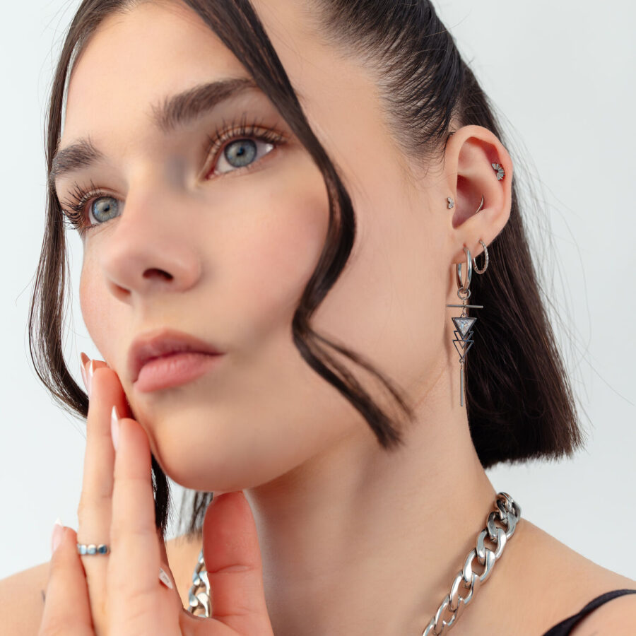 Mujer con aros Artdeco plateados y colgante de cadena, retrato cercano