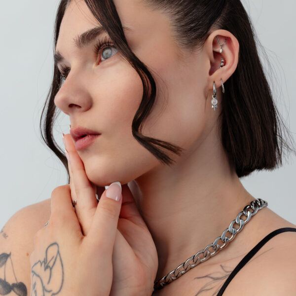 Mujer con Mini Lollipop aros, pelo corto, tatuajes, fondo blanco