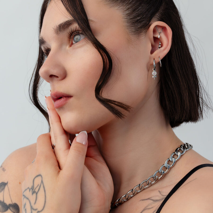 Mujer con Mini Lollipop aros, pelo corto, tatuajes, fondo blanco