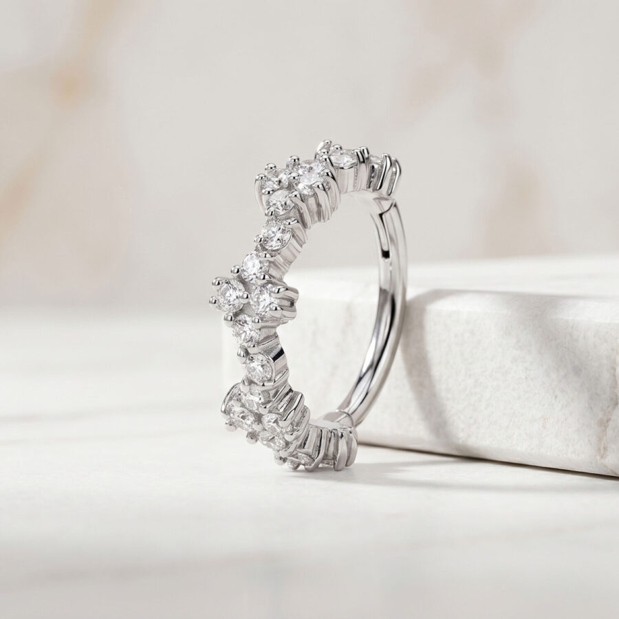 Anillo de piercing plateado con cristales claros sobre un fondo de mármol blanco