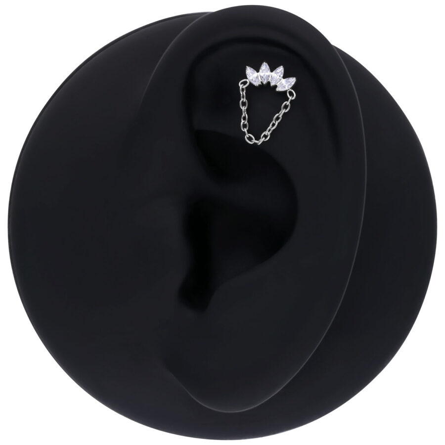 Accesorio de corona de cristal plateada con cadena en una oreja negra sobre fondo blanco