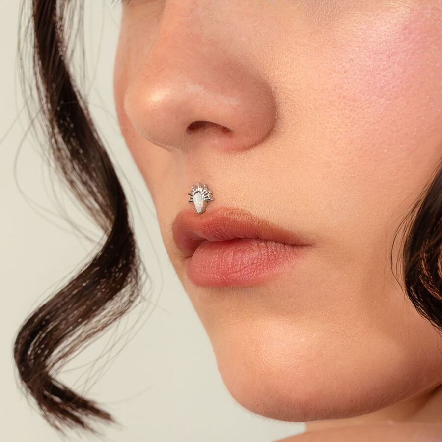 Primer plano de un piercing nasal con ajuste de rayos de sol de ópalo en oro blanco