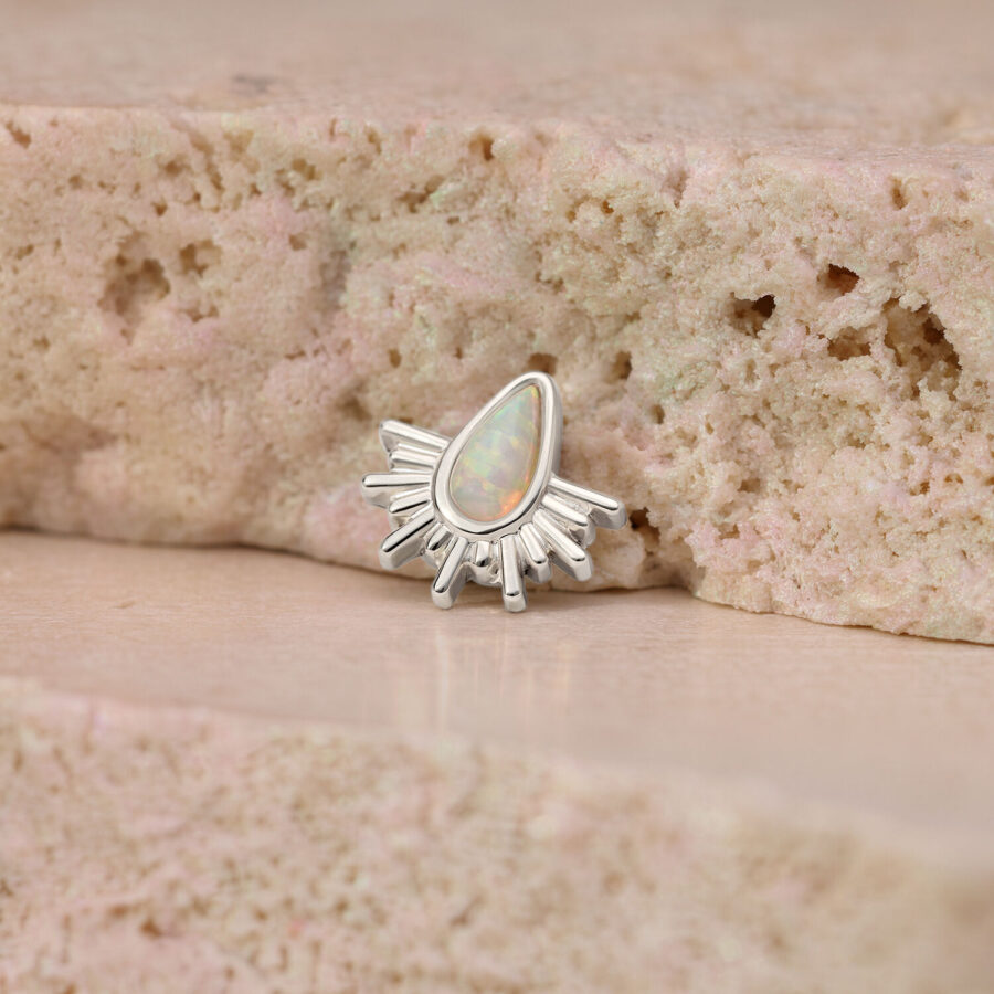 Adorno de piercing de oro blanco con ópalo sintético en forma de rayos de sol sobre piedra rosa