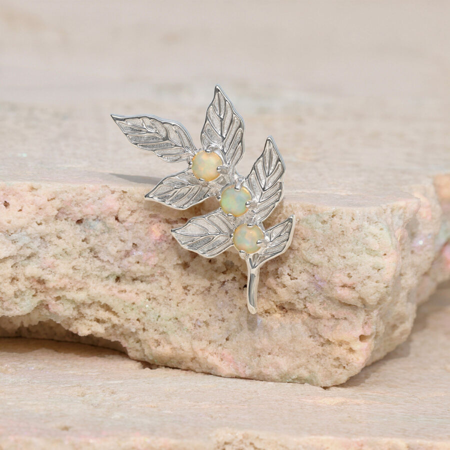 Colgante en forma de hoja con piedras de ópalo sobre piedra beige