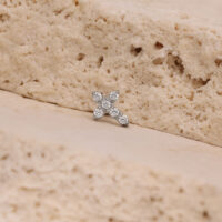 Pequeño accesorio de cruz de cristal, plata Pequeño accesorio de cruz de cristal plateado sobre superficie de piedra beige