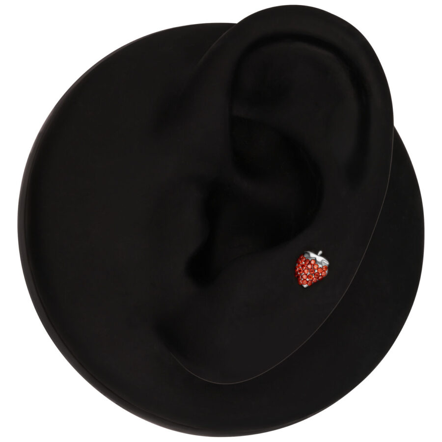 Oreja negra con accesorio de piercing de fresa sobre fondo negro