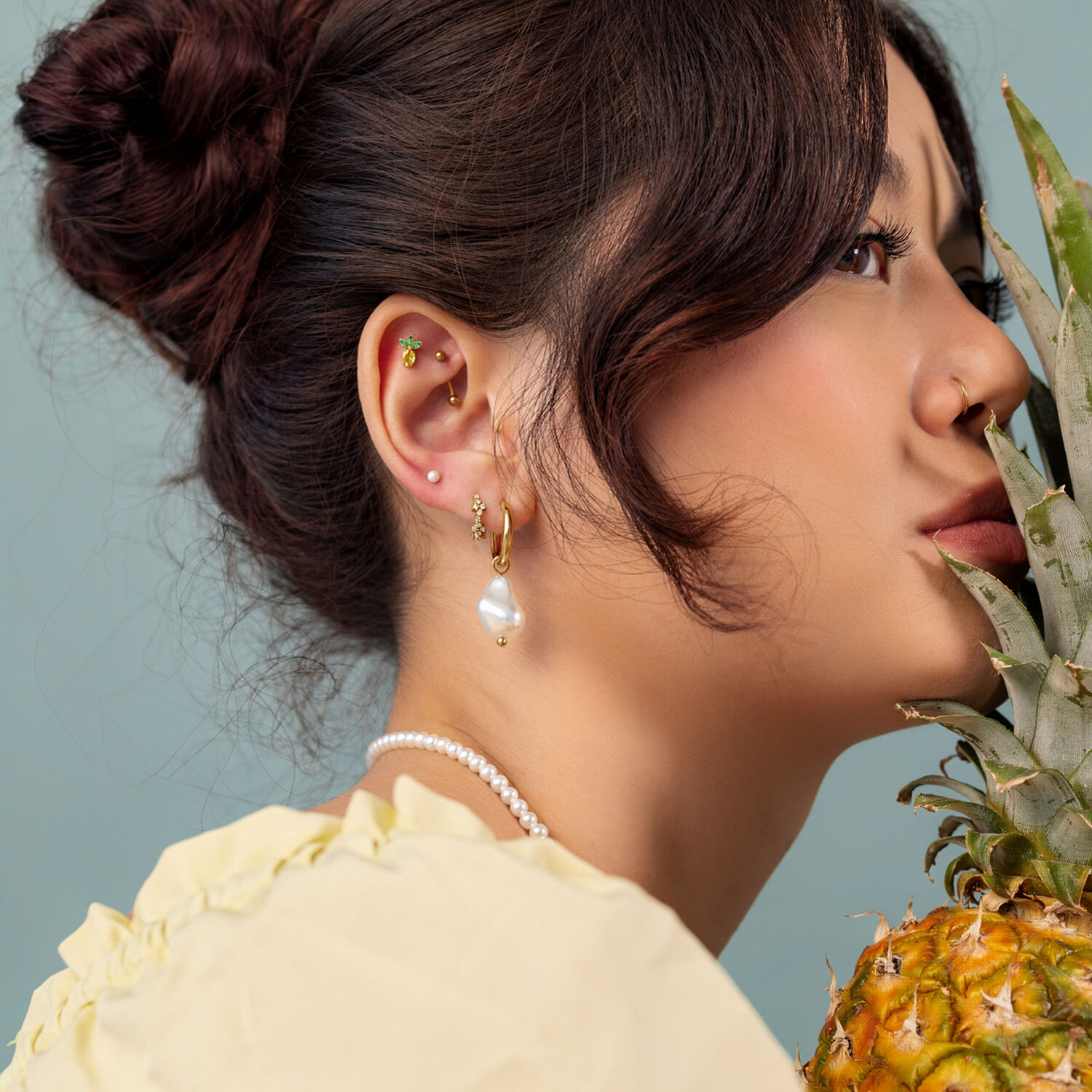 Ajuste a presión de piña dorada Mujer con pendientes dorados y un adorno de piña, perfil lateral