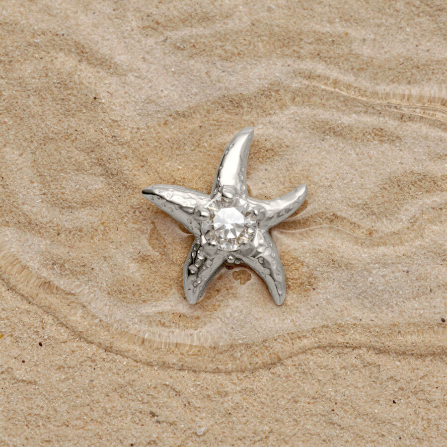 Accesorio de estrella de mar plateada con cristal sobre arena