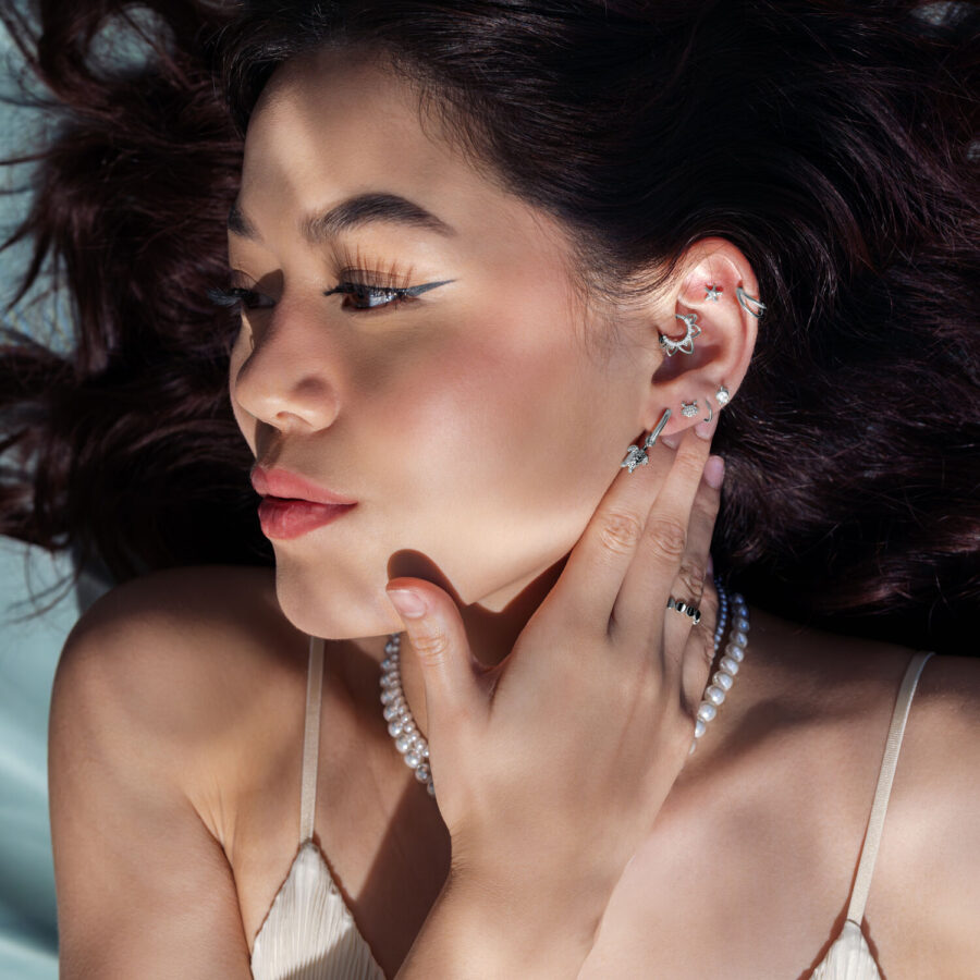 Mujer con varios accesorios de piercing plateados en la oreja, lleva joyas de perlas