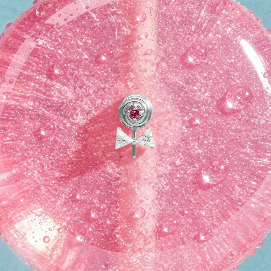 Accesorio Lollipop plateado con piedra rosa sobre fondo rosa brillante