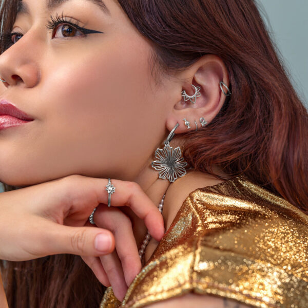 Mujer con varios pendientes y piercings de plata, ropa dorada
