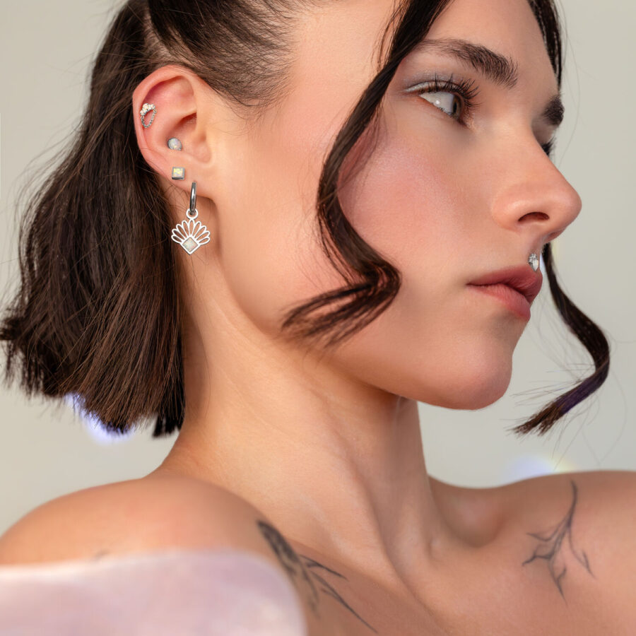 Mujer con cabello corto lleva aplique ovalado de ópalo en plata en la oreja