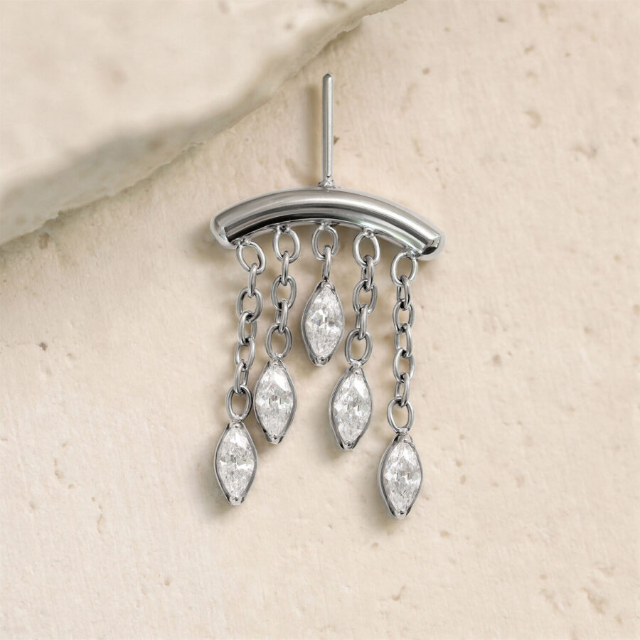 Accesorio plateado con cinco gotas de cristal claro en cadenas sobre fondo claro