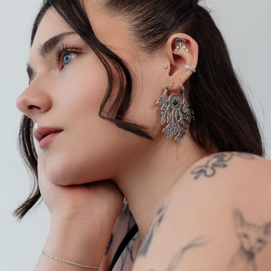 Mujer con accesorios de piercing plateados en la oreja, de perfil