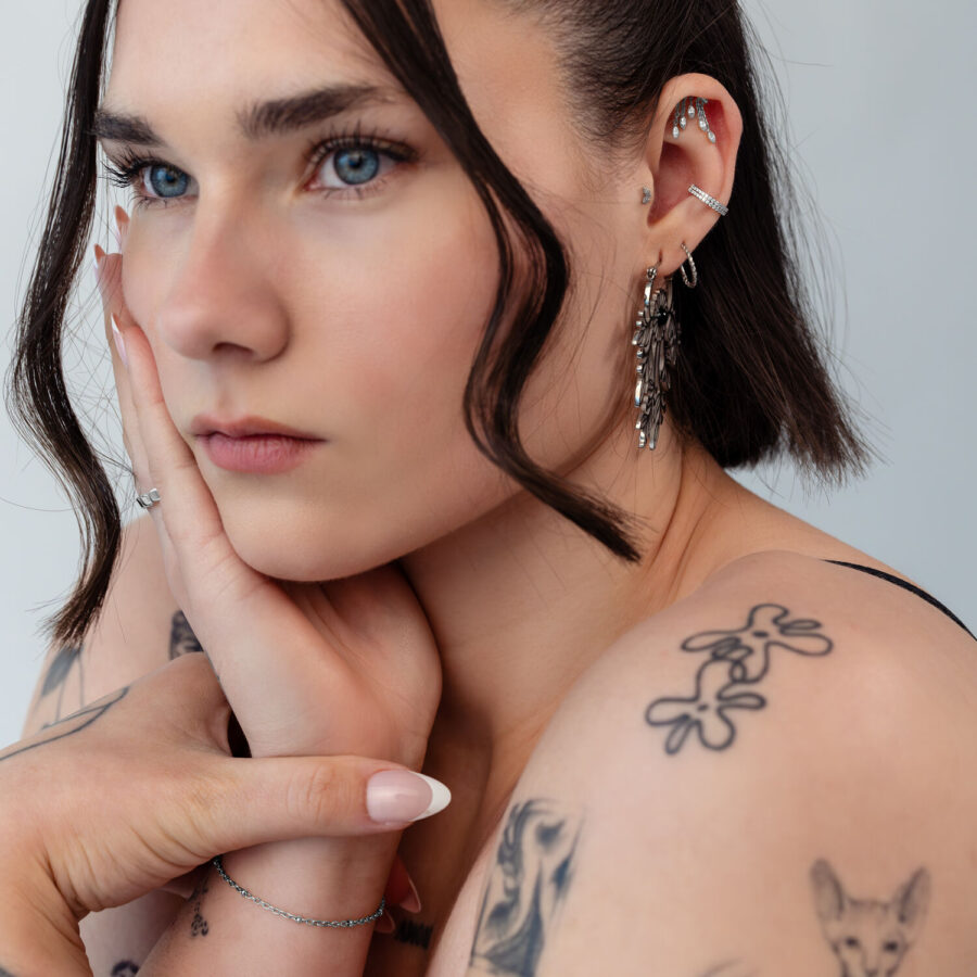 Mujer con varios piercings en la oreja, incluyendo un accesorio Helix plateado, primer plano