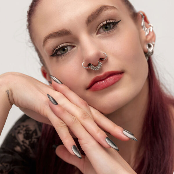 Mujer pelirroja con un septum clicker plateado con bolas decorativas