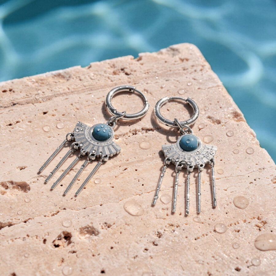 Pendientes de plata con detalles de turquesa sobre piedra mojada junto a la piscina
