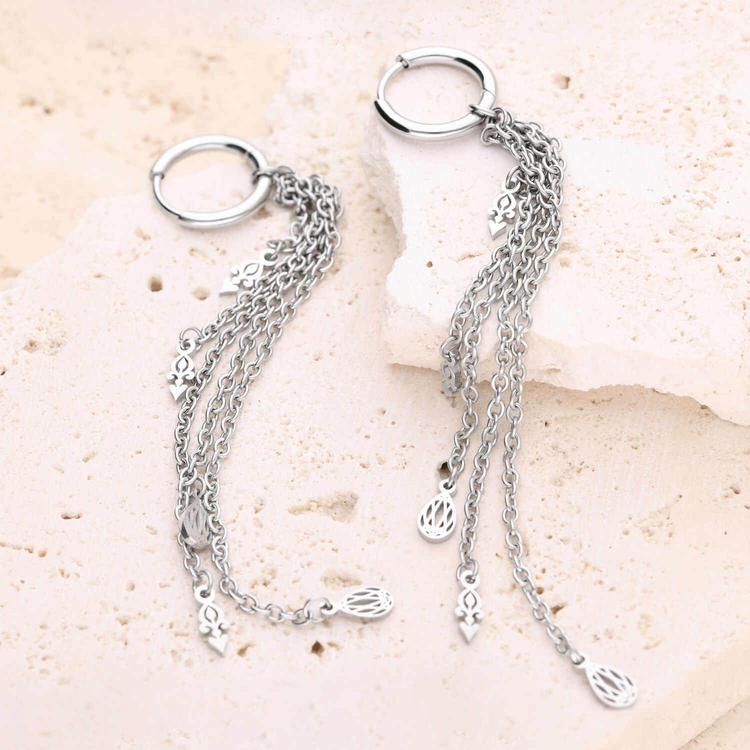 Pendientes de plata con colgante de cadena Dos pendientes de plata con cadenas colgantes sobre piedra clara