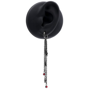 Pendiente negro con largas cadenas y acentos rojos en una oreja de modelo