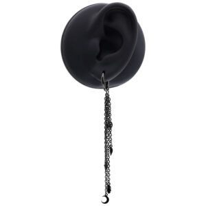 Pendiente negro con cadenas largas en una oreja artificial sobre fondo blanco