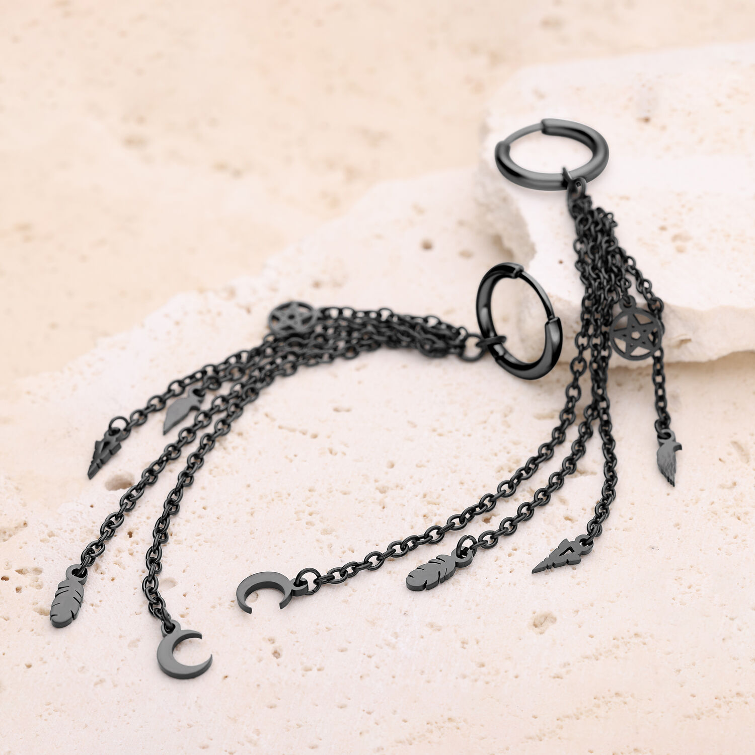 Pendientes negros de acero inoxidable con colgantes Pendientes negros de acero inoxidable con cadenas y colgantes sobre piedra clara