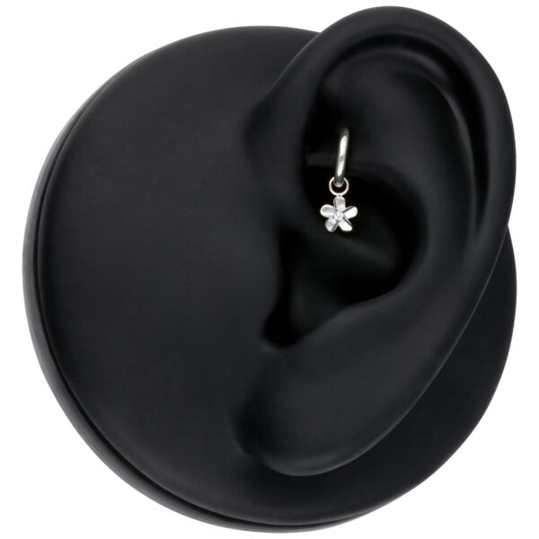 Colgante de flor plateada en un modelo de oreja negra, primer plano