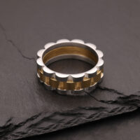Anillo de plata y oro de acero quirúrgico sobre piedra oscura