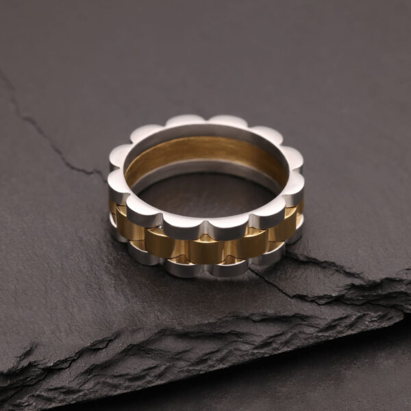 Anillo de plata y oro de acero quirúrgico sobre piedra oscura
