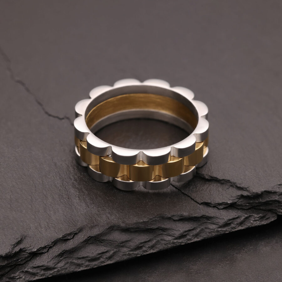 Anillo de plata y oro de acero quirúrgico sobre piedra oscura