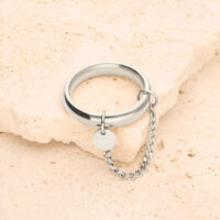 Anillo de plata con pequeña cadena y colgante redondo sobre piedra clara