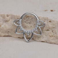 Clicker de septum plateado con diseño floral y cristales sobre piedra clara