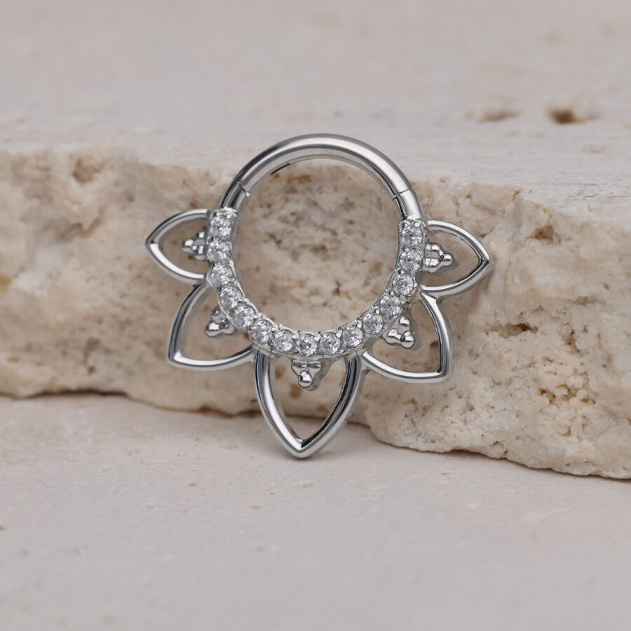 Clicker de septum plateado con diseño floral y cristales sobre piedra clara