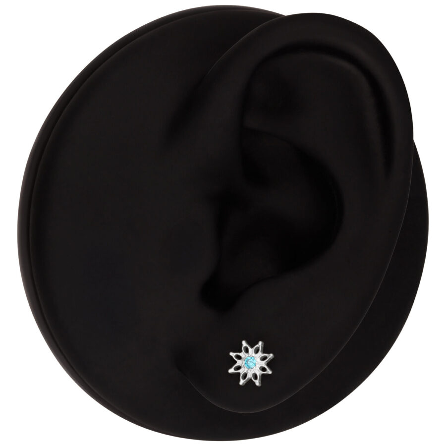 Modelo de oreja negra con adorno de flor de cristal turquesa en el lóbulo