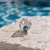 Ajuste de concha de oro blanco con turquesa Ajuste de concha de oro blanco con cristal turquesa sobre una piedra mojada en la piscina