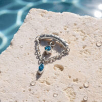 Doble Adorno de Piercing de Turquesa Adorno de piercing de hélice plateado con dos piedras turquesas sobre piedra clara con gotas de agua