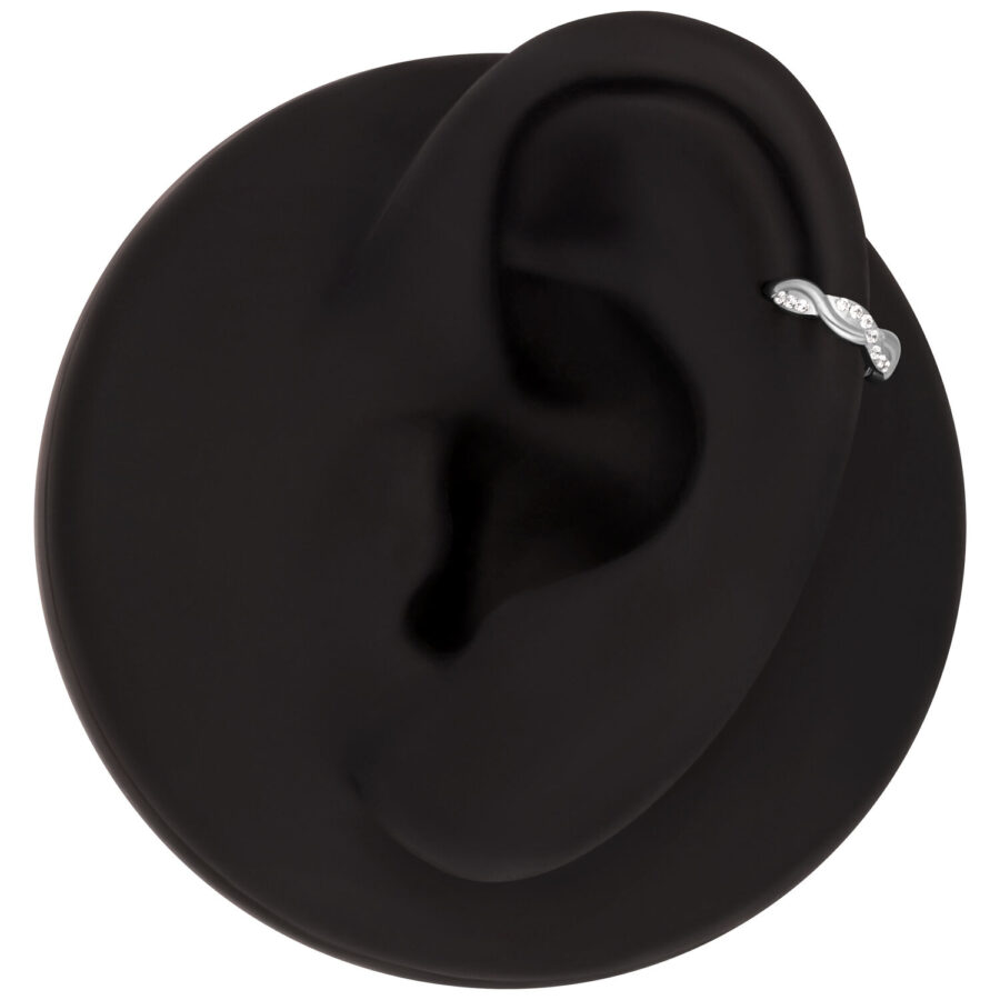 Modelo de oreja negra con un clicker de piercing ondulado de titanio y cristales claros, sobre fondo negro