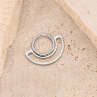 Clicker de Doble Anillo Plateado sobre Piedra Clicker de anillo plateado sobre fondo de piedra beige, diseño circular