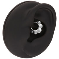 Modelo de oreja negra con anillo de flor plateado sobre fondo blanco