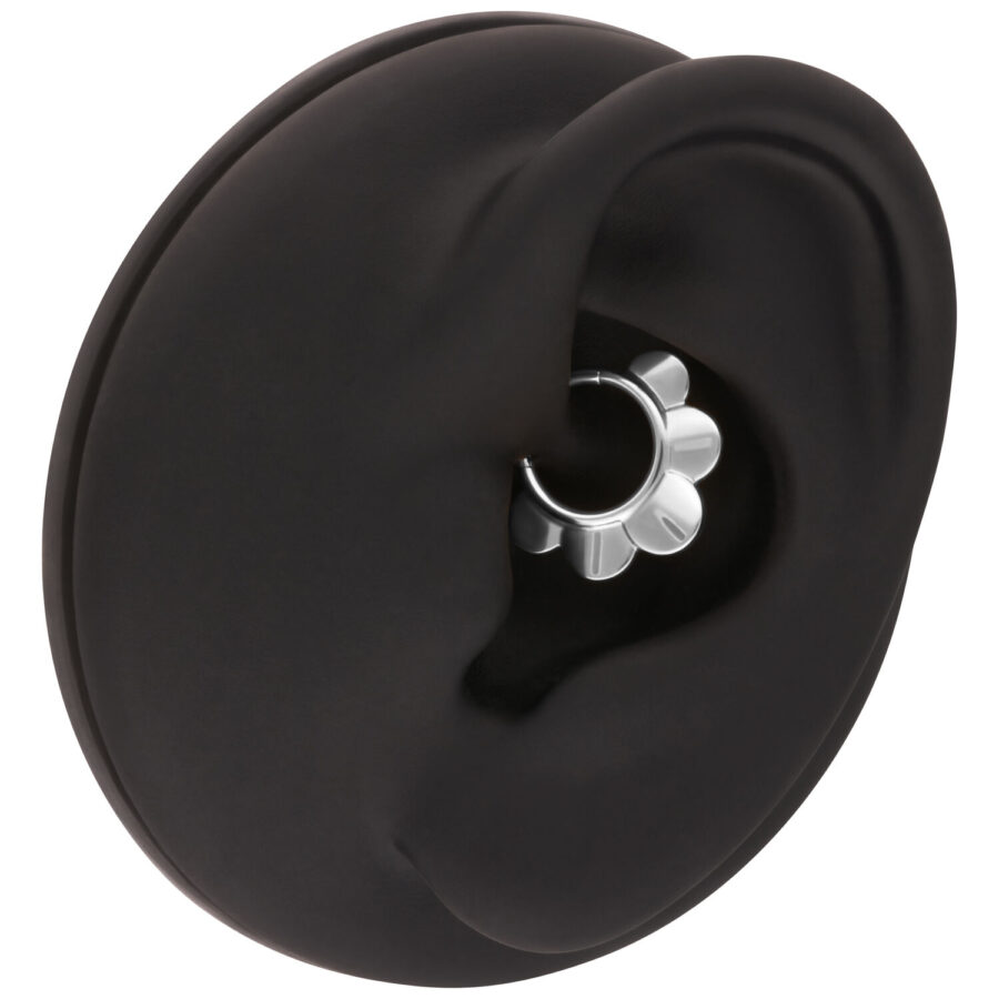 Modelo de oreja negra con anillo de flor plateado sobre fondo blanco