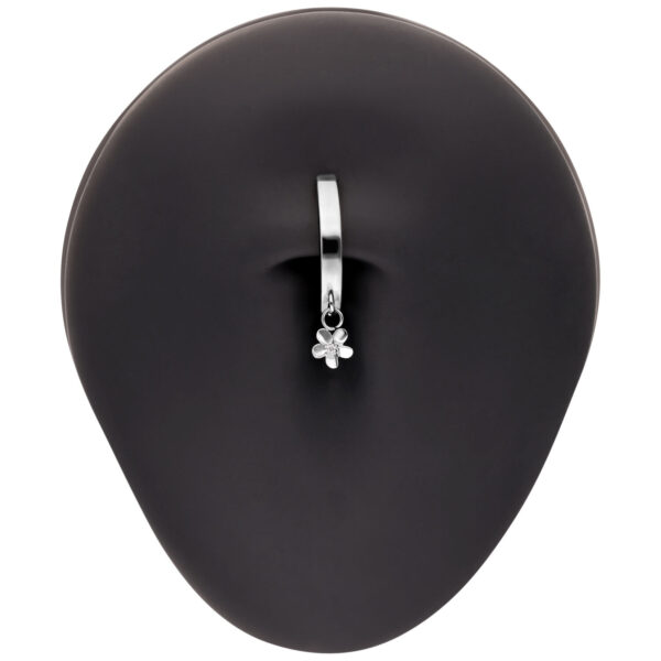 Clicker de ombligo de plata con un pequeño colgante de flor sobre fondo negro