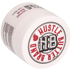 Lata blanca con la marca Hustle Butter y letras rojas, tumbada de lado