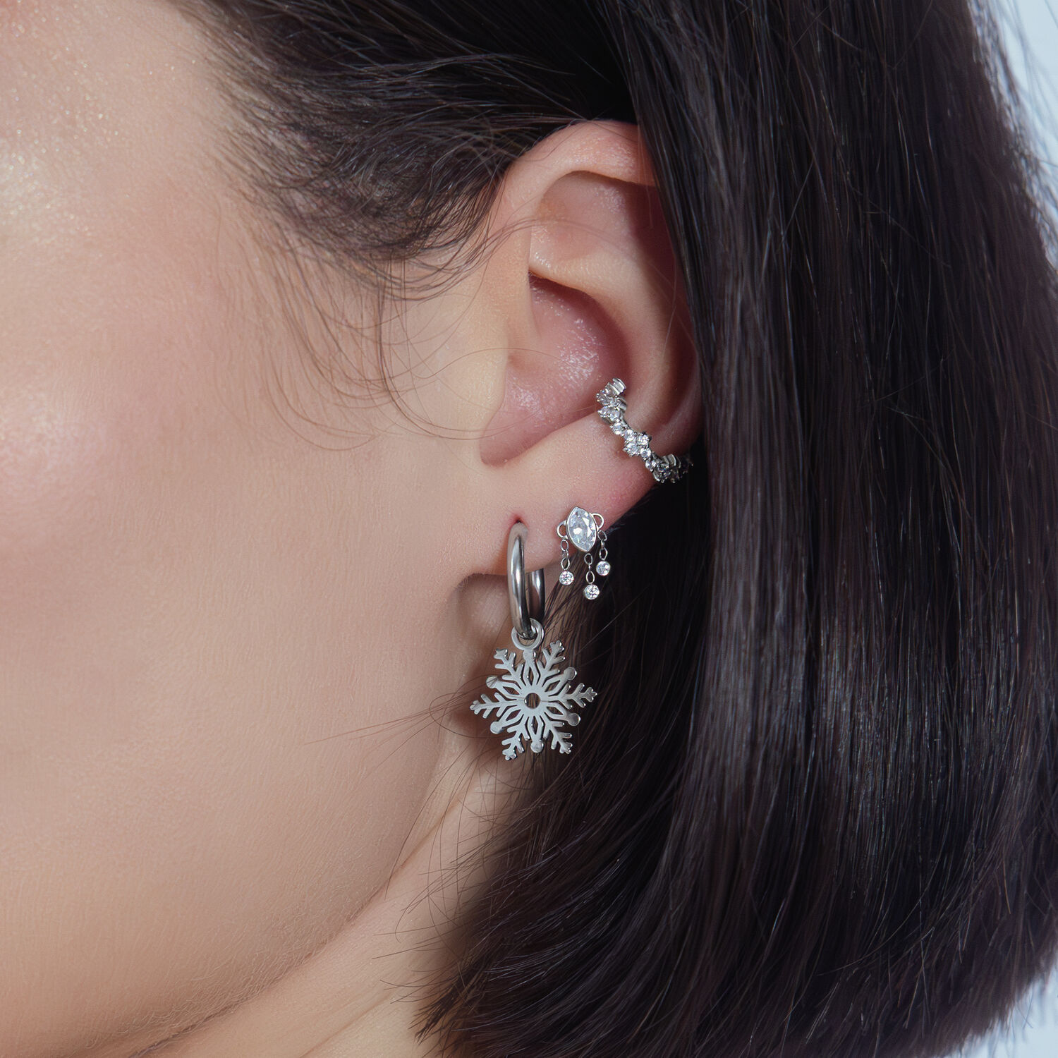 Elegante colgante de cristal para piercing de oreja Colgante de cristal plateado en la oreja con otros piercings sobre fondo blanco
