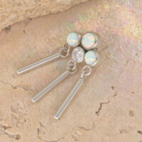 Coronilla de oro blanco con ópalos sintéticos y circonitas sobre fondo de piedra beige