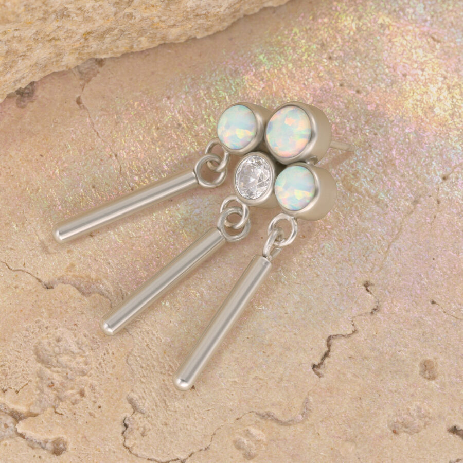 Coronilla de oro blanco con ópalos sintéticos y circonitas sobre fondo de piedra beige