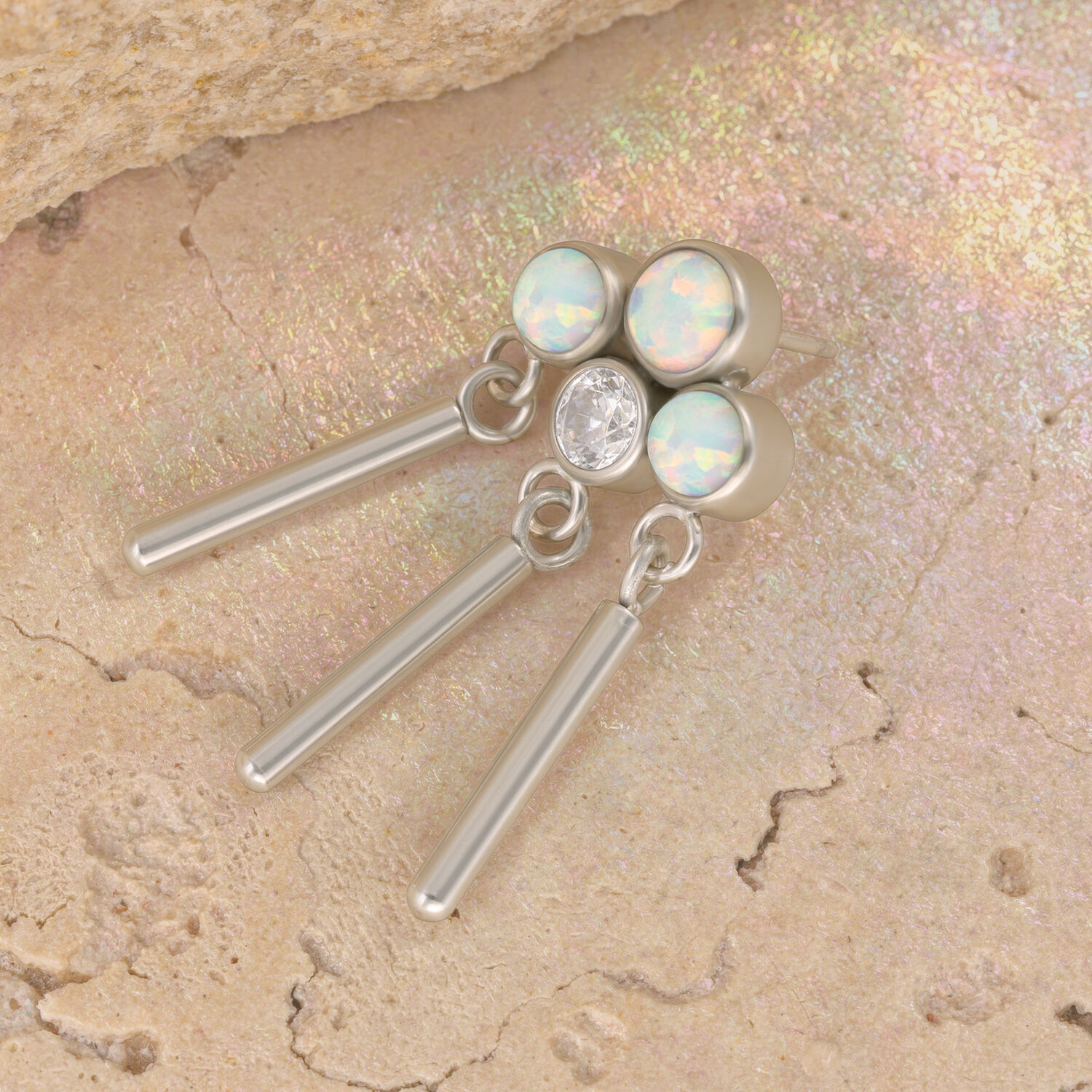 Coronilla de oro blanco con ópalos sintéticos y circonitas sobre fondo de piedra beige
