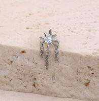 Accesorio de piercing en forma de estrella plateada con cadenas sobre superficie de piedra clara