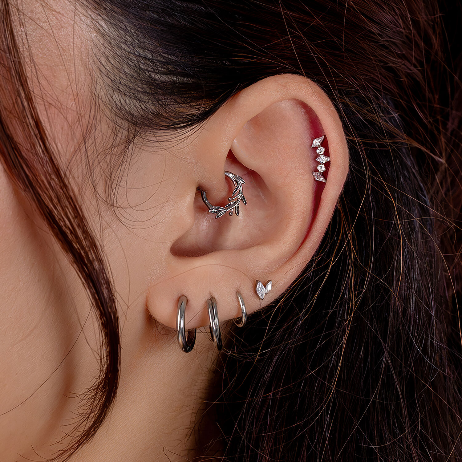 Pendientes de piercing plateados con cristales Oreja con varios piercings plateados, incluyendo cadena de cristales y anillos